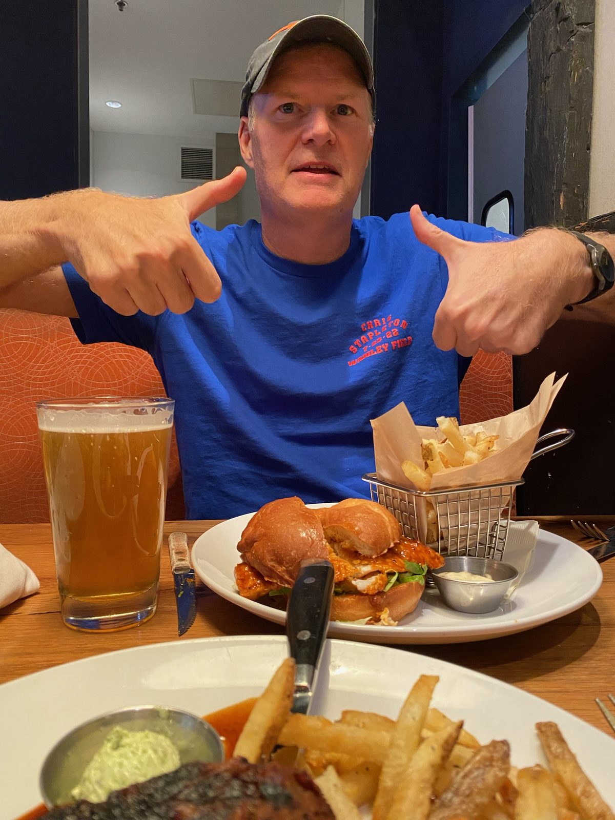 Todd giving two thumbs up to a chicken sandwich and a beer